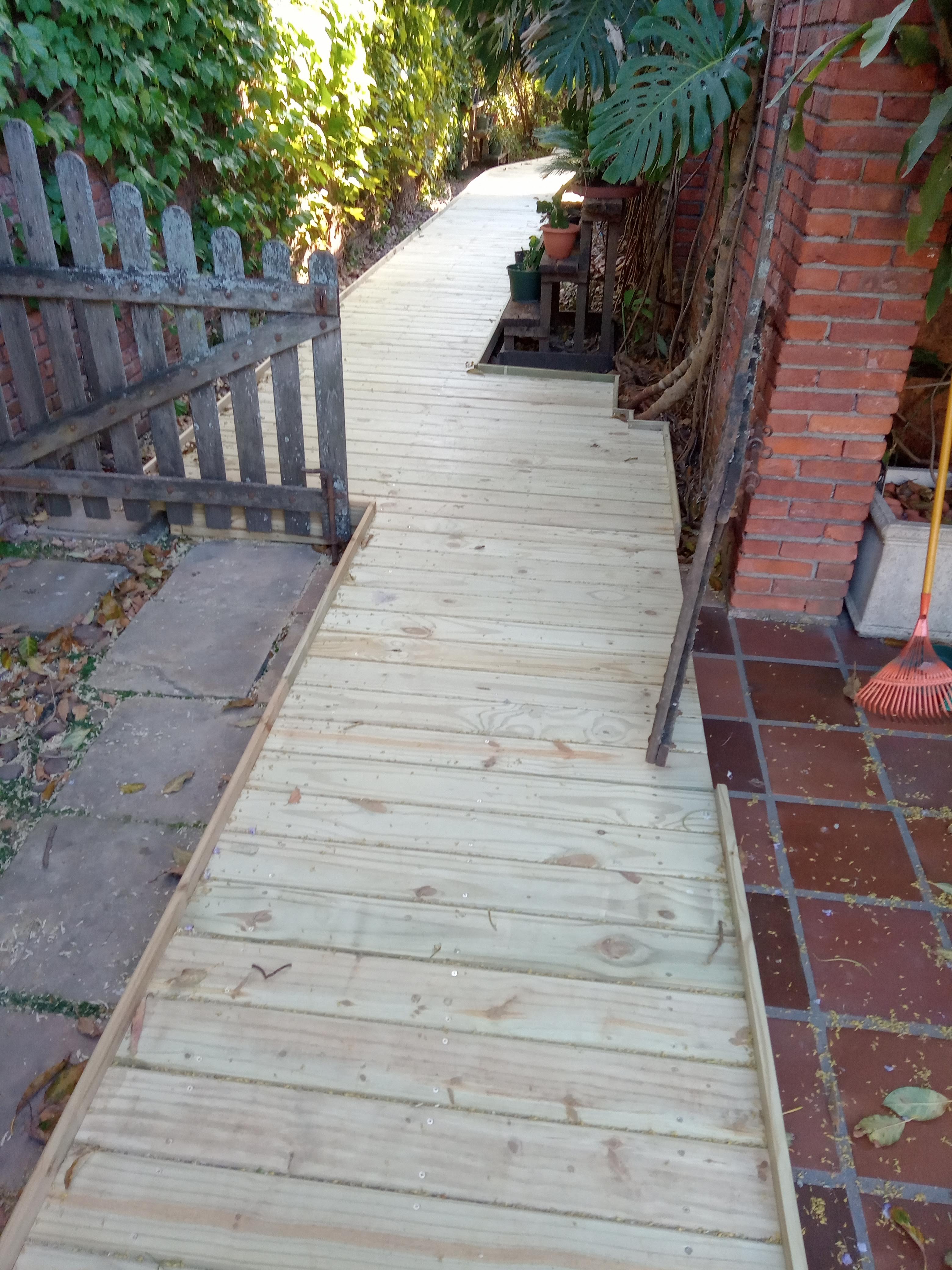 Pasillo exterior con deck de madera tratada a medida