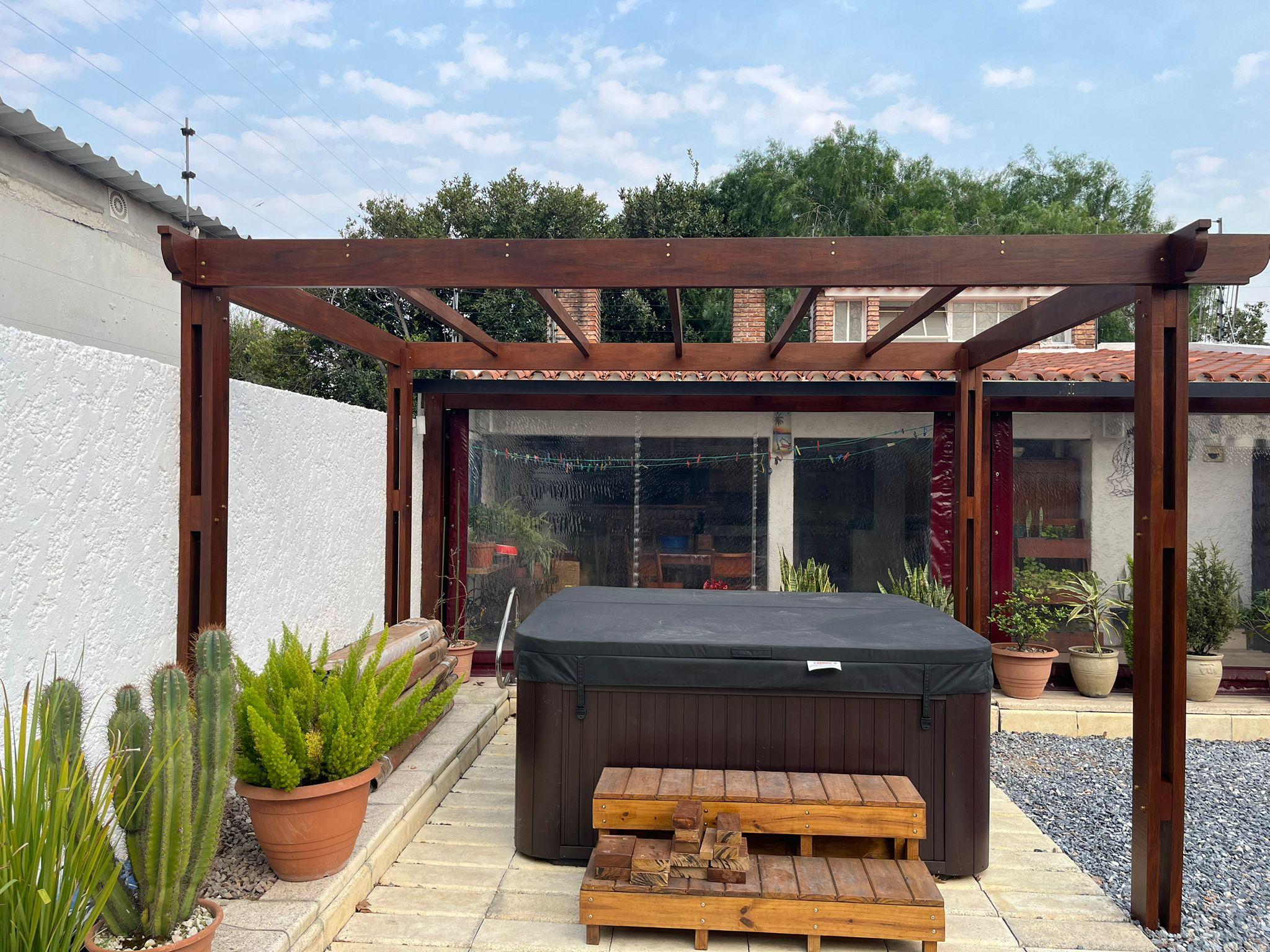 Pérgola de madera oscura con deck y jacuzzi